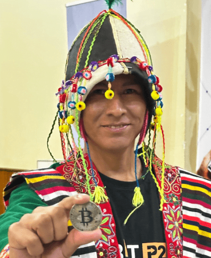 A person in a typical Bolivian costume shows off a physical bitcoin coin.