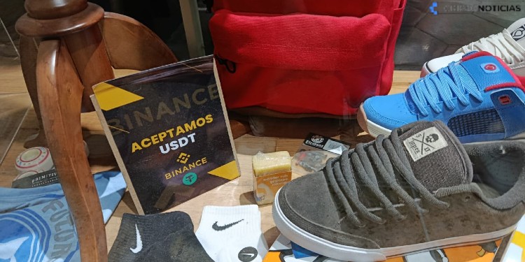Photograph of a store that sells shoes, socks and has a sign that says "we accept USDT".